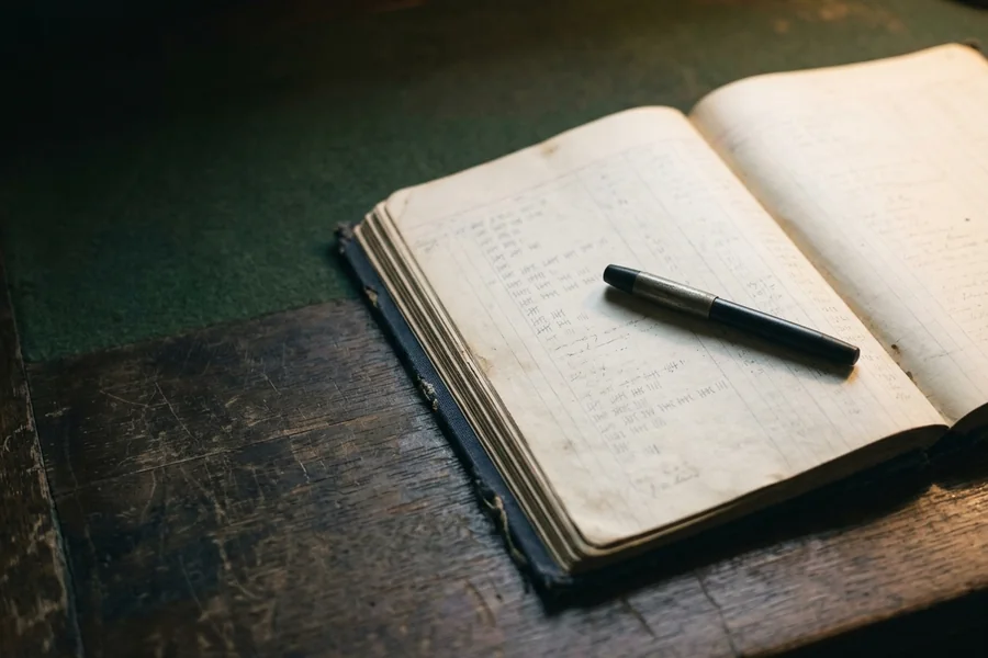Fountain pen and gold wax seal on a black leather ledger